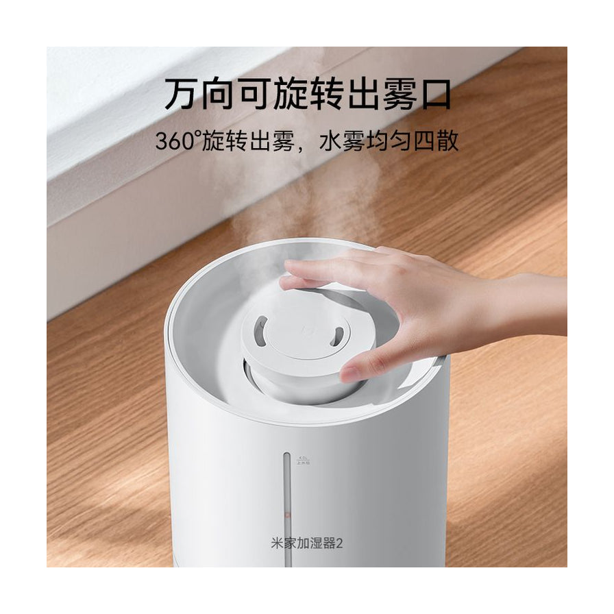 小米米家加湿器2顶部特写，展示万向可旋转出雾口设计，手部正在调节出雾方向。