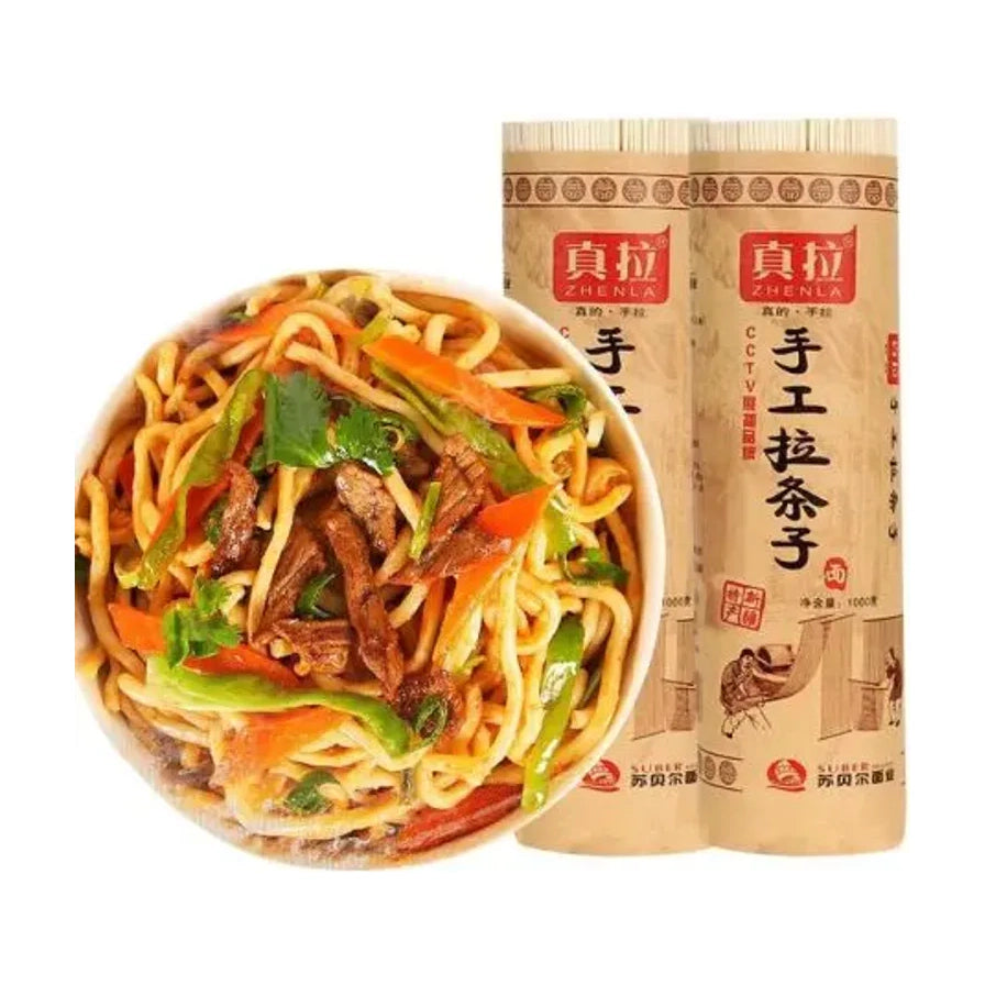 真拉手工拉条子面1kg包装，背景为两卷牛皮纸包装的干面条，前景为一碗拌好的新疆拉条子面，配有肉片、青椒和红椒。