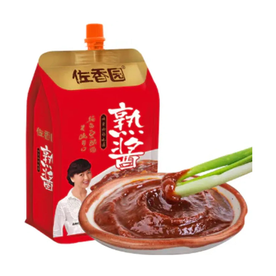佐香园熟酱产品与蘸酱场景展示，前景为盛在碗中的深褐色酱料及大葱蘸取特写，背景为产品包装。